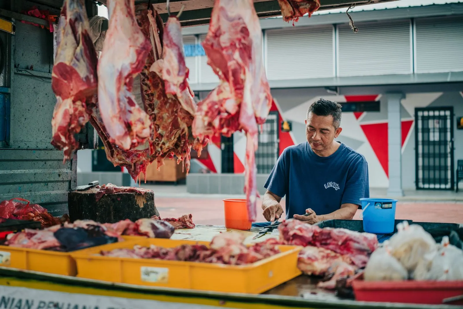 A meat vendor preparing cuts at the Labis morning market in Johor, Malaysia. Traditional outdoor scene.